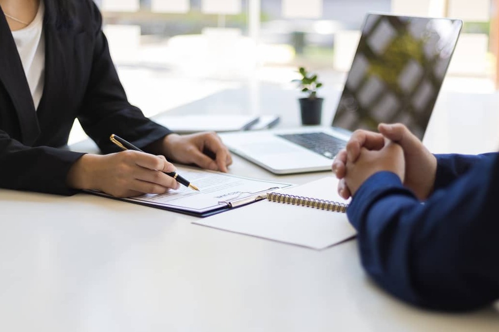 The manager is reading the resume and is interviewing the new employee. Negotiating business and signing a contract. Lawyer and legal advisor.